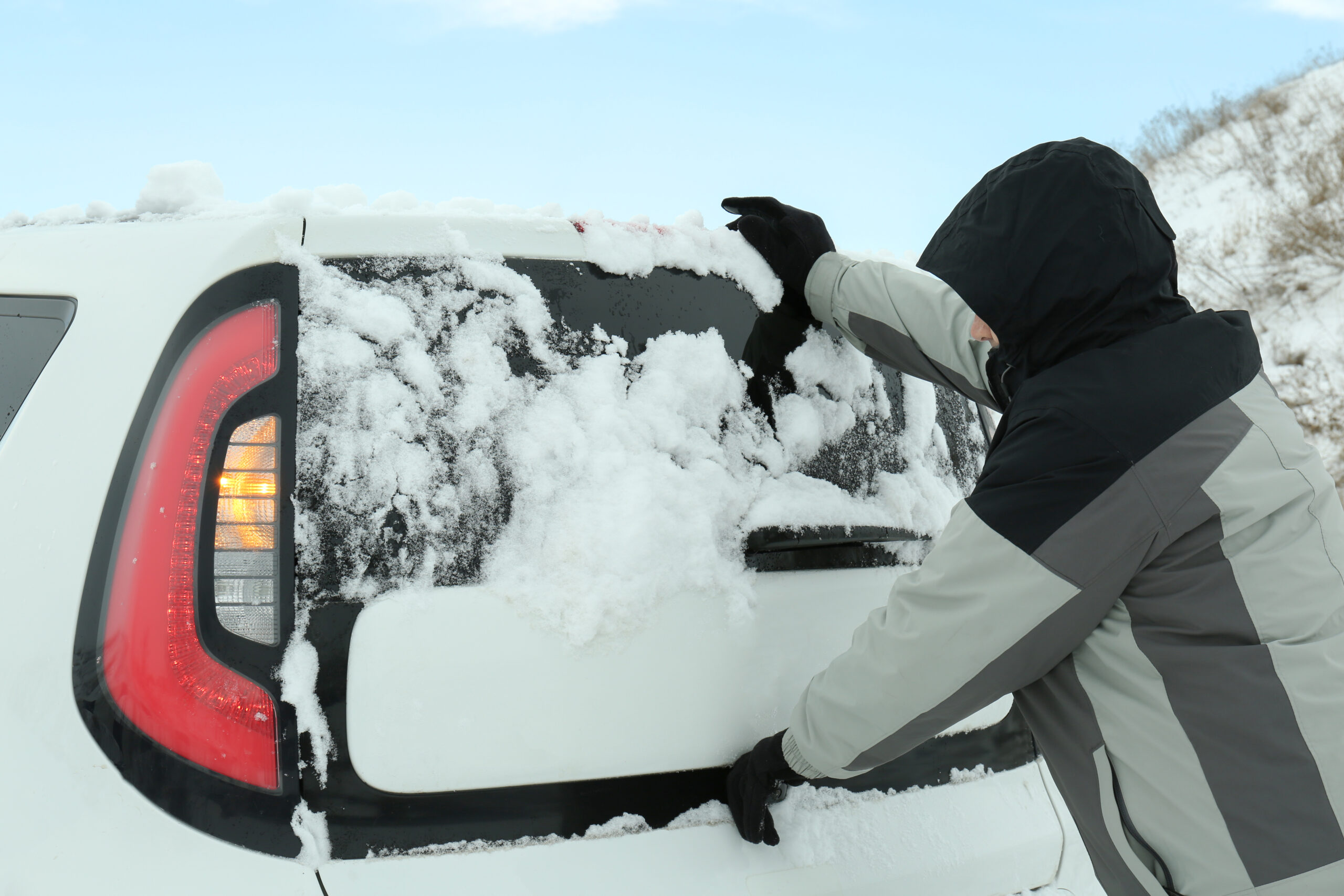 man pushing car stuck snow winter road